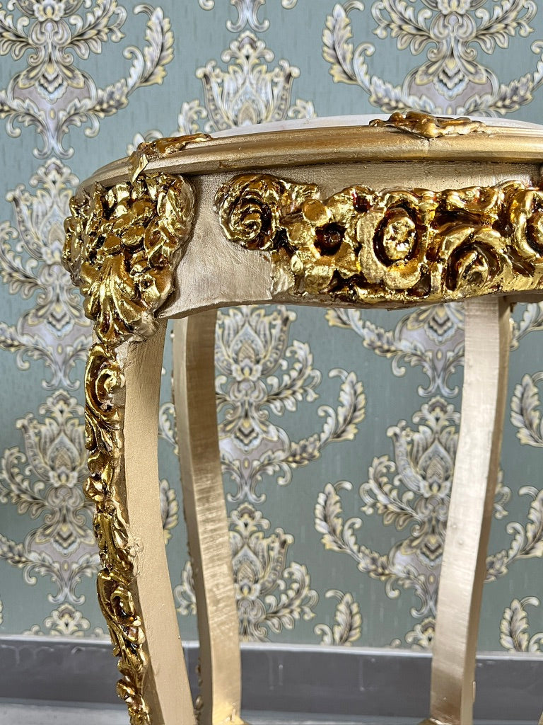 Small gold end table with beige marble top and hand-carved gold gilded details, used as a decorative side table.
