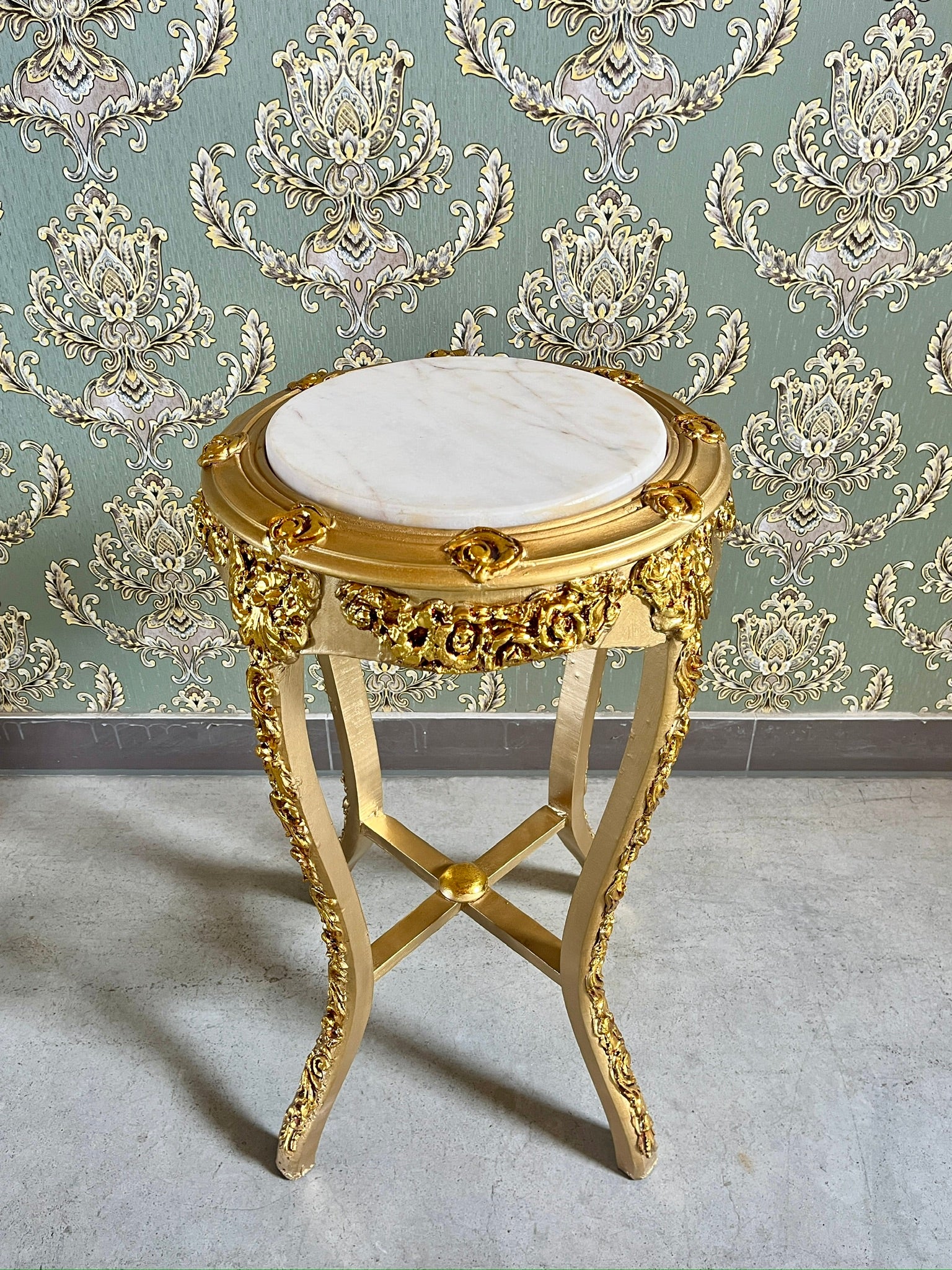Small gold end table with beige marble top and hand-carved gold gilded accents, stylish furniture piece.